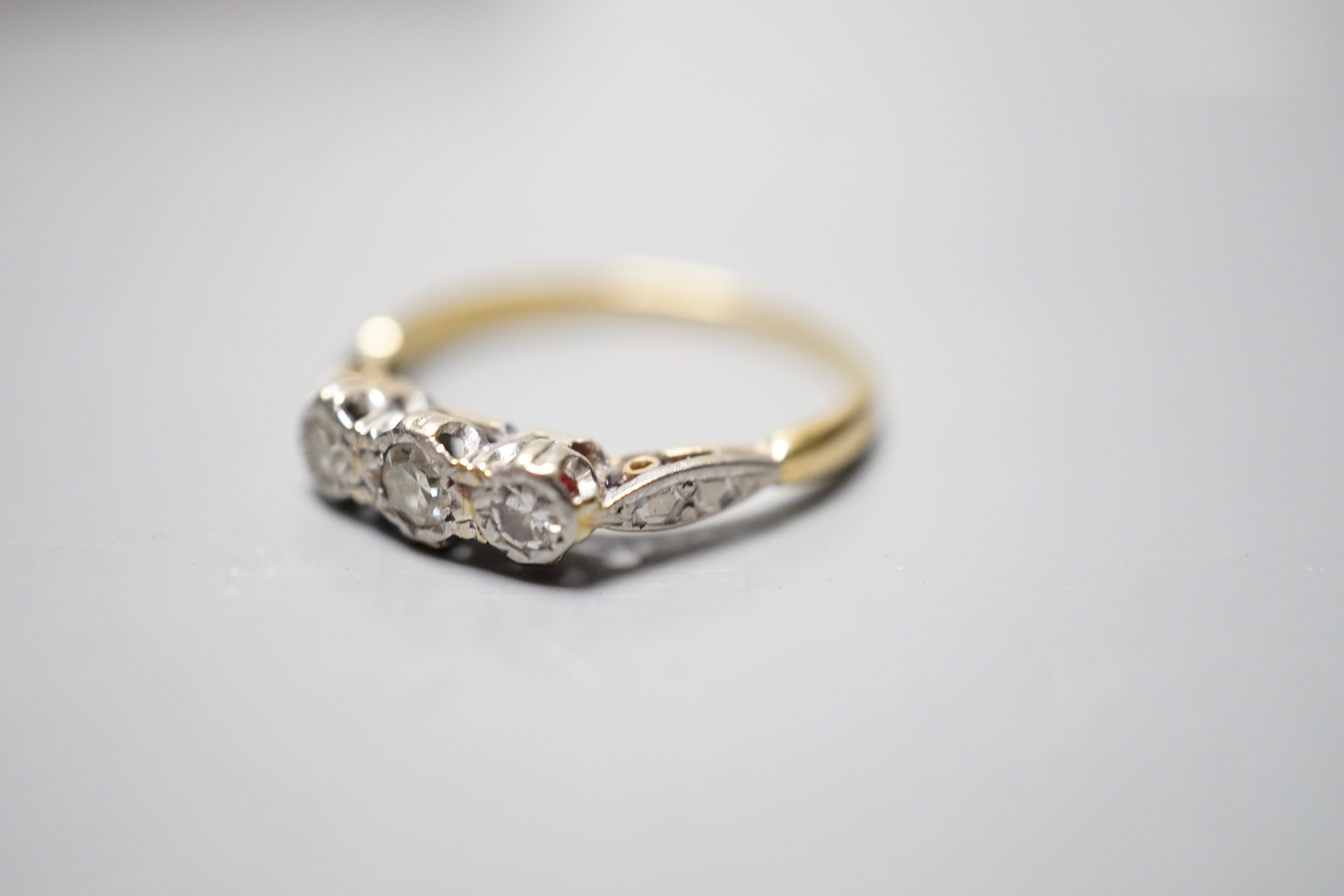 A yellow metal and illusion set three stone diamond ring, size O, gross weight 2.4 grams.